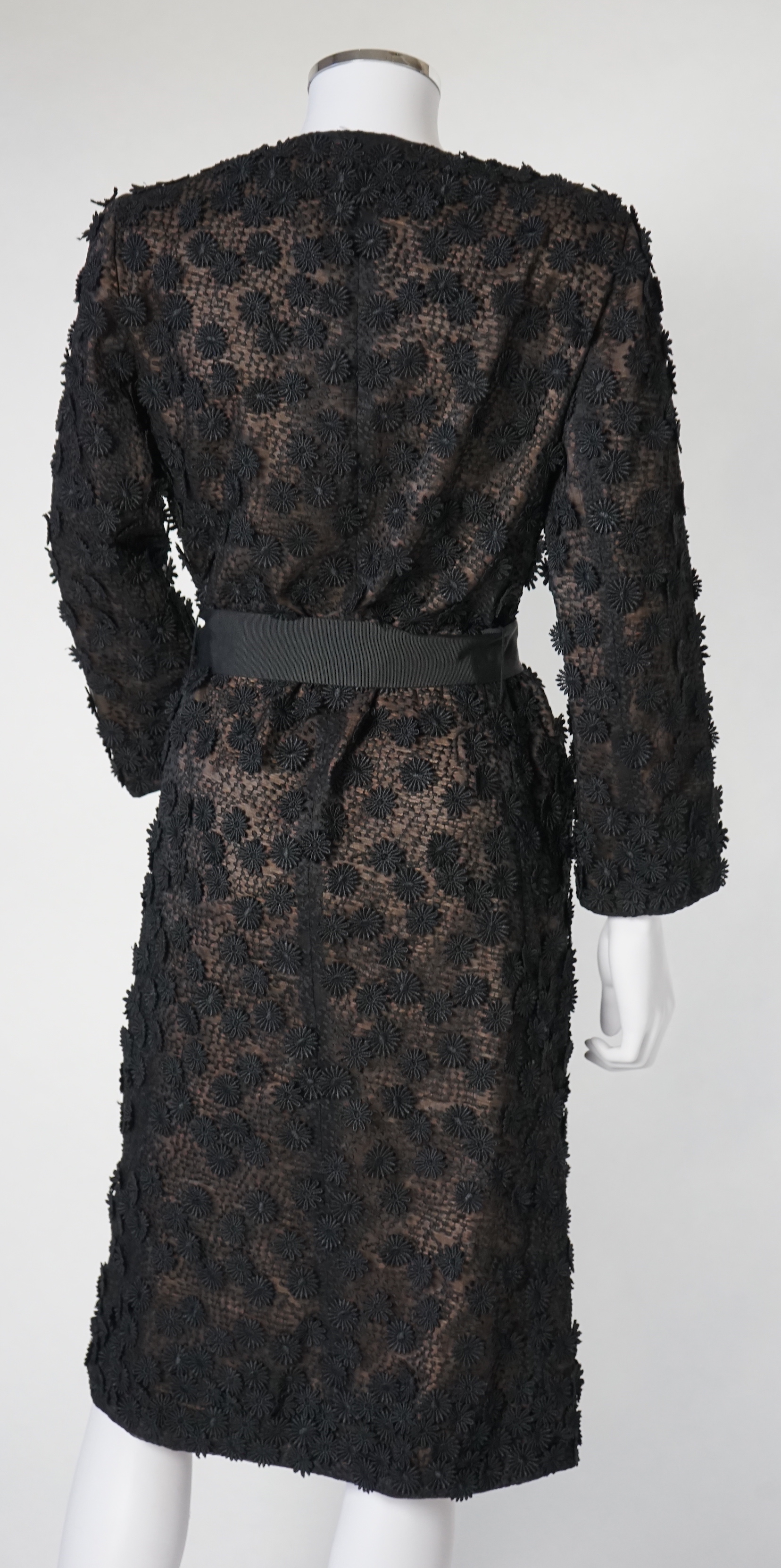 A Nicole Farhi lady's black lace knee length jacket with flower embellishment all over with black ribbon tie belt, size 12